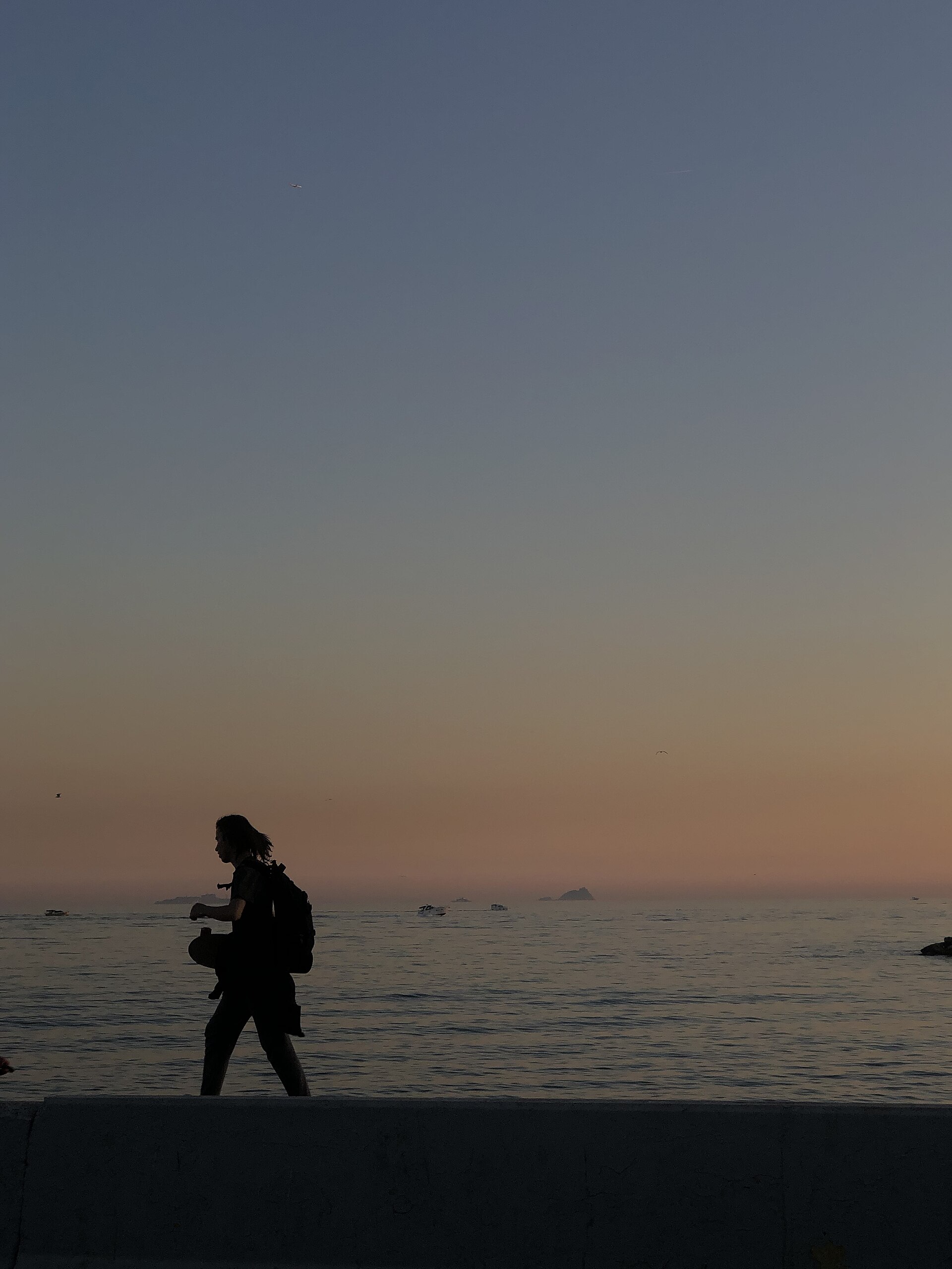 A person walking along the Moda sea wall at dusk, the Marmara Sea and the Princes’ Islands behind