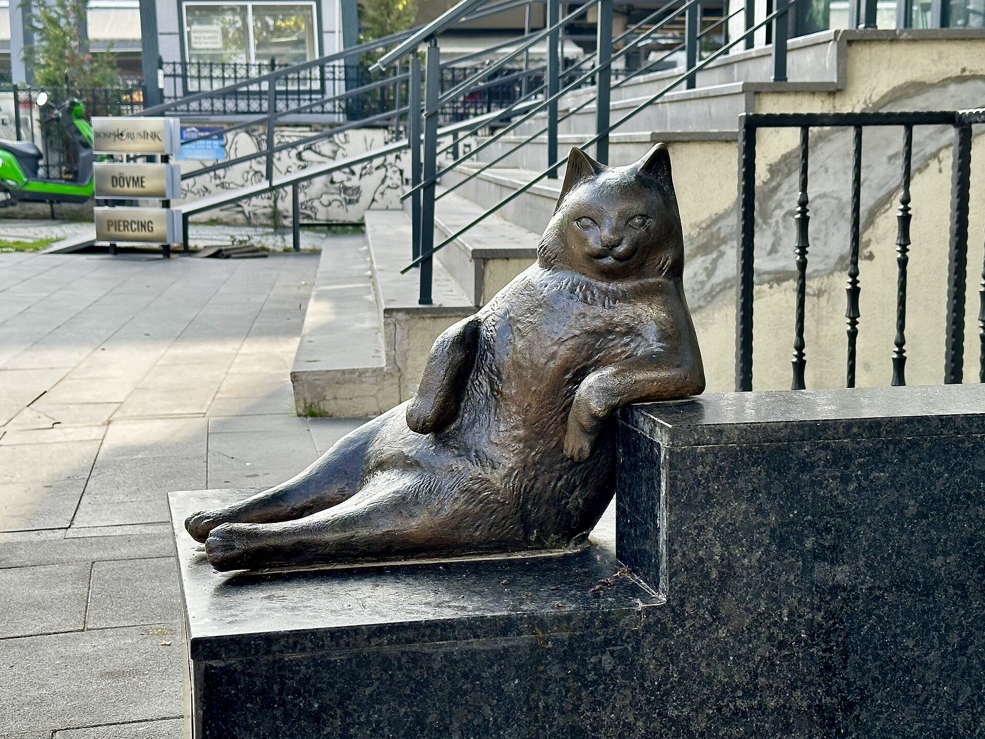 The bronze statue of Tombili the cat, reclining with one paw on a granite kerb, on a Kadıköy pavement