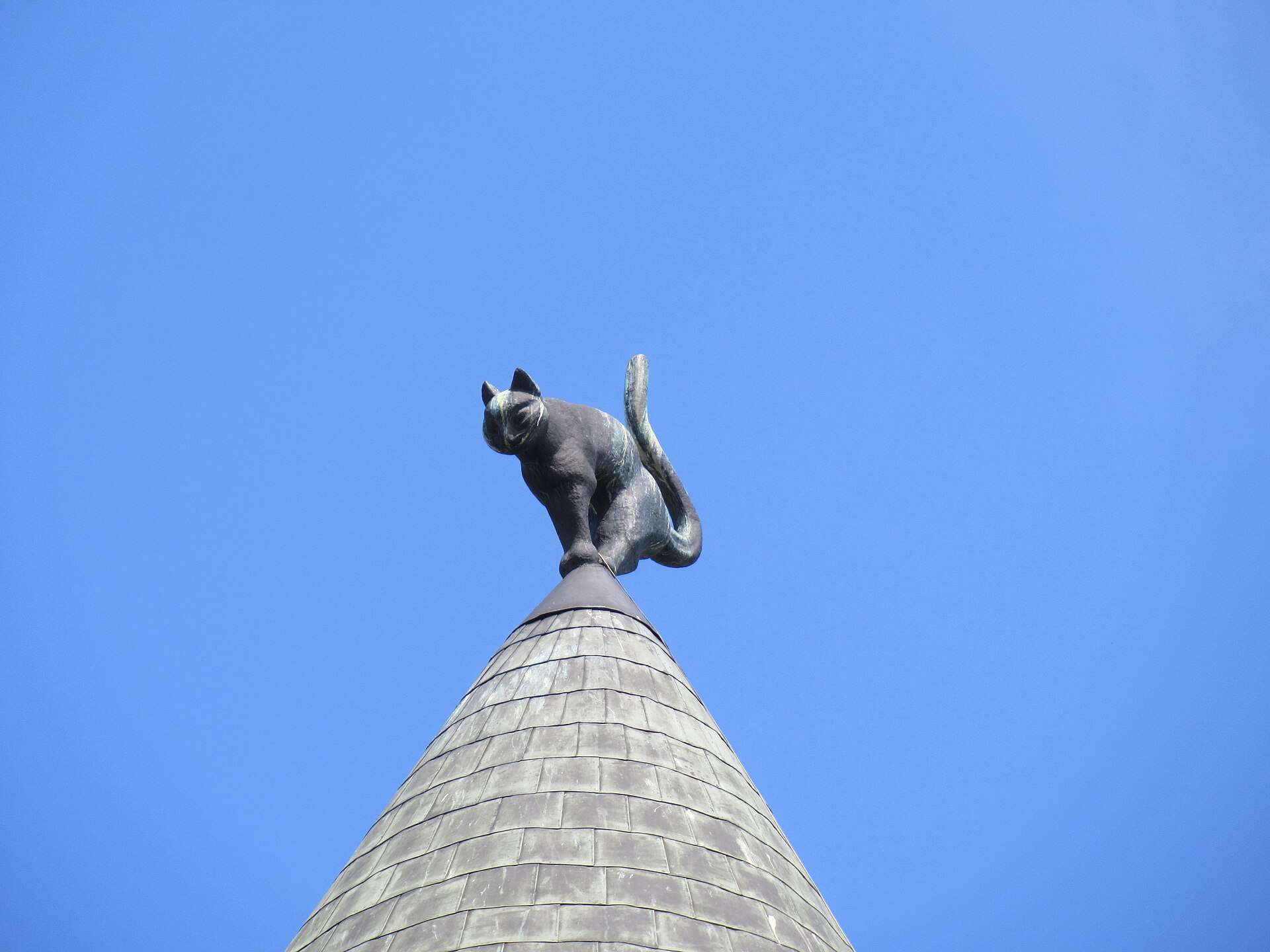 The copper cat on the turret of the Cat House in Riga, arched against the sky