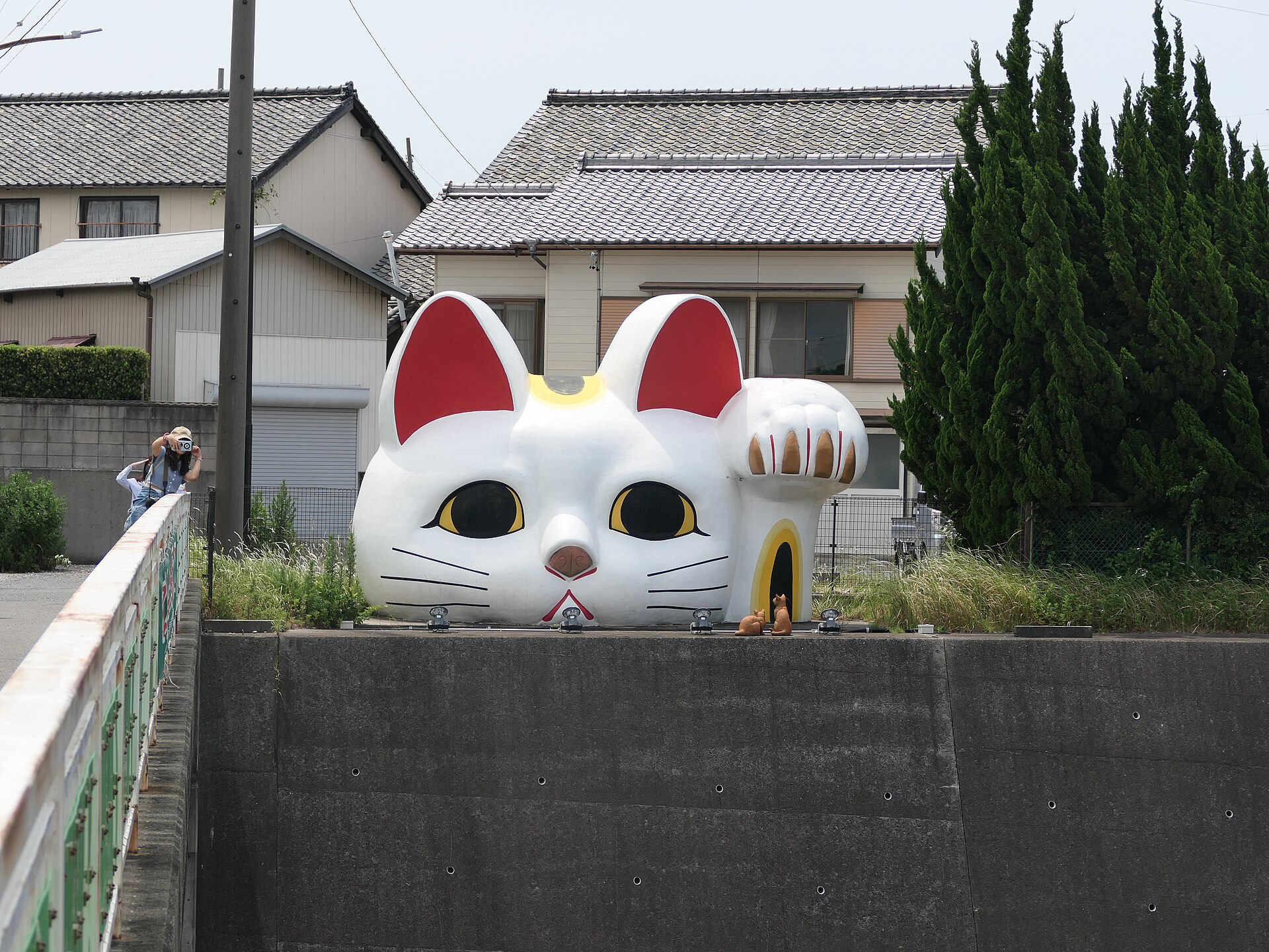 Tokonyan, the giant ceramic lucky cat of Tokoname, peering over a wall